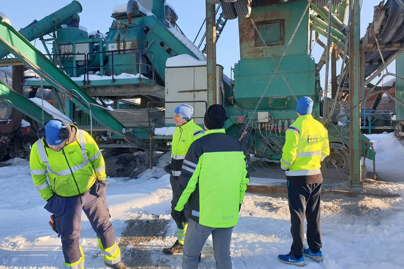 En grupp anställda på EKAV som står och pratar med varandra på en byggarbetsplats.